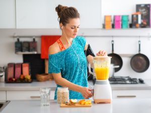 Fit woman in kitchen making a smoothie