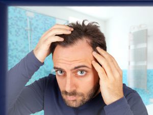 Man looking at hair in the mirror