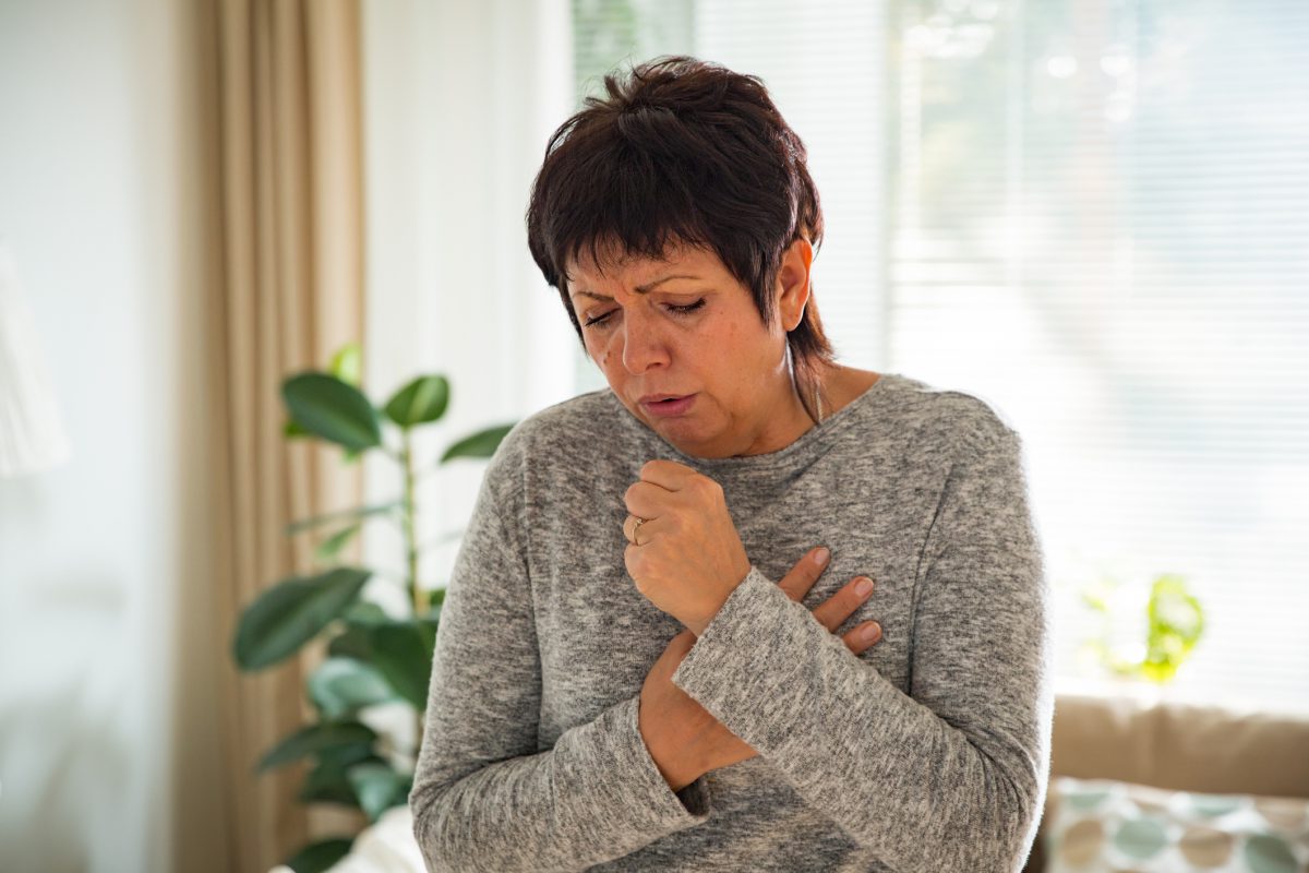 woman coughing, holding chest